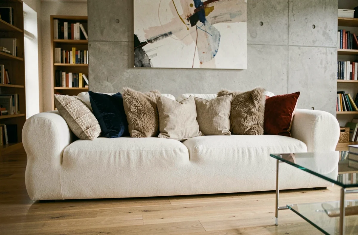 Canapé nuage blanc surchargé de coussins dépareillés dans un salon moderne mal agencé, erreurs de décoration à éviter